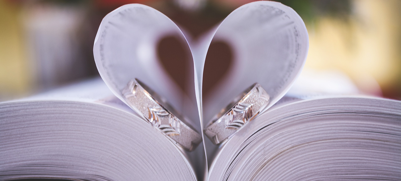 A bible with weddings rings hidden in pages that are shaped as a heart