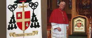 Bishop Crosby standing next to the Cathedra displaying his coat of arms.