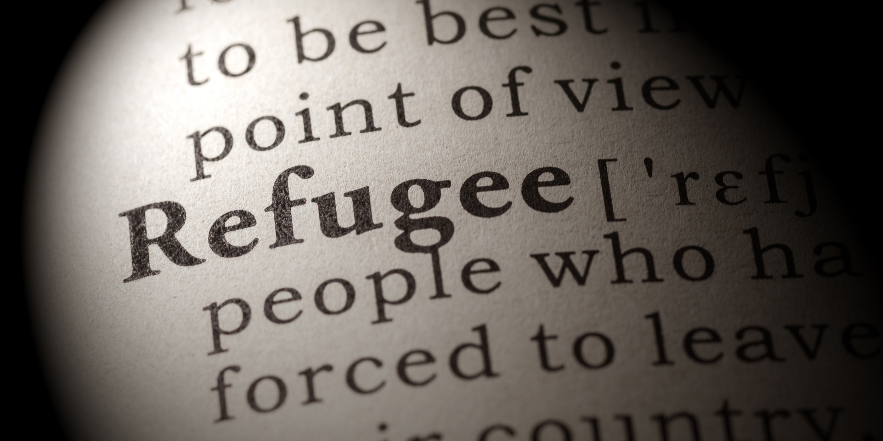Close up on a page in the dictionary with the definition of the word Refugee