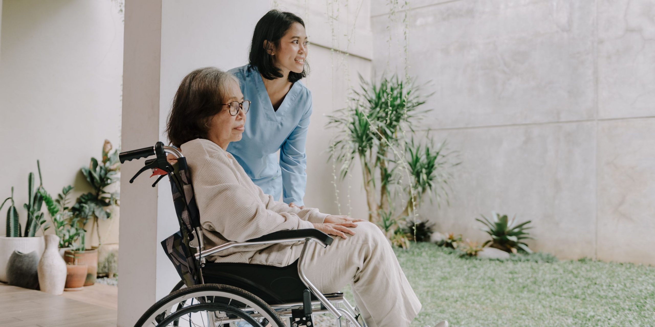 care giver and woman in wheelchair looking at garden
