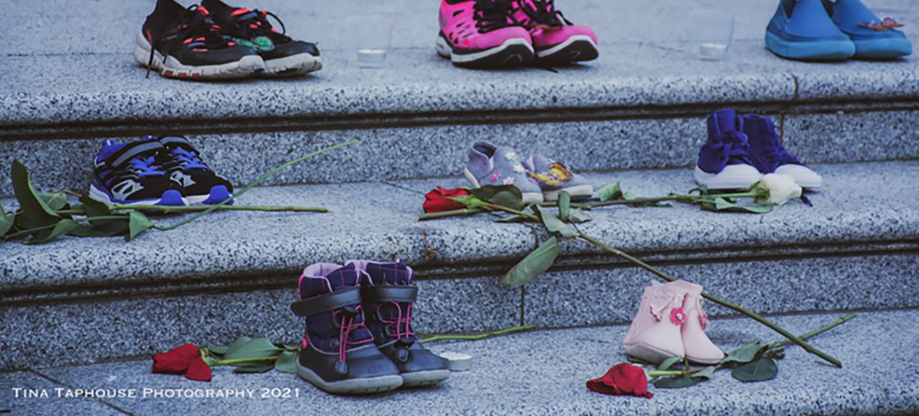 Children shoes on steps with roses as memorial