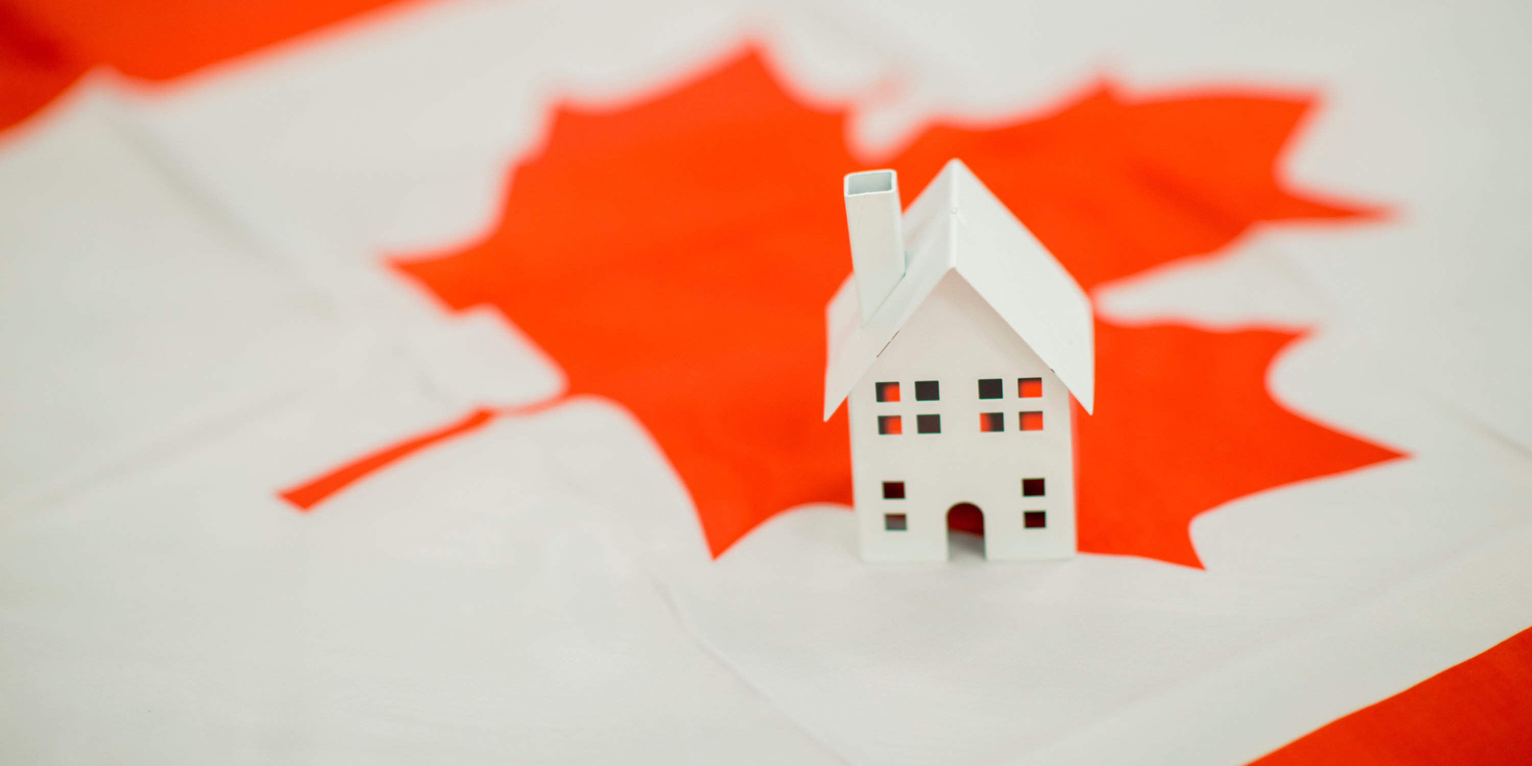 Miniature figurine of a home placed atop of a Canadian flag