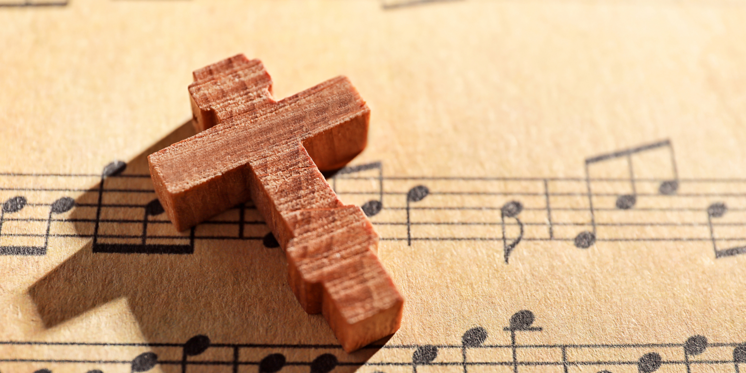 A wooden cross sits atop of a page with musical notes.