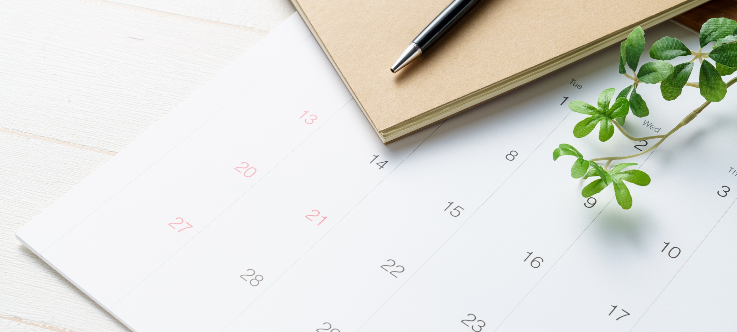 An image of a month of a calendar with a file folder, pen and plant branch overlaid on top of it